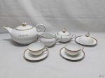 Jogo de servir chá tete a tete com 6 peças em porcelana Schmidt com friso ouro. Peças gravadas "M. Peixoto". Composto de bule, leiteira, açucareiro, manteigueira e 2 xícaras com pires.