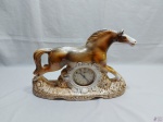Lindo enfeite na forma de cavalo em porcelana ricamente trabalhado com relevos, possui um relógio despertador. Medindo o cavalo 45,5cm de comprimento x 14,5cm de profundidade x 31cm de altura.
