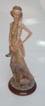 Belíssima escultura em resina representando Dama com seu cão de marca Vênus Arte, gravada na base. Mede 40 cm x 13 cm.
