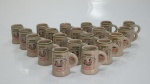 Conjunto com 20 canecas em porcelana para servir cachaça da marca São Joaquim, com a inscrição Cachaça Manuel e Joaquim, medindo 5,5 cm x 6 cm.