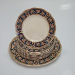 Jogo para bolo em porcelana com dez peças da marca Grindley England com decoração em flores e frisos de ouro, medindo a maior peça 25 cm de diâmetro. Apresentam marcas do tempo e quatro pratos com bicados.