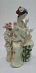 Belíssima escultura de gueixa em porcelana na cor marfim com rica decoração floral em relevo, medindo 41cm  x 25 cm.