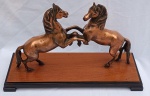 Belíssimo grupo escultórico com dois cavalos em bronze e base em madeira nobre, medindo 47 cm x 31 cm x 18 cm.