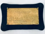Placa em metal dourado Westinghouse Air Brake Company, U.S.A., Divers Air Compressor, com moldura em madeira. Med. 26x39 cm.