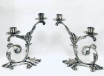 Par de candelabros para duas velas, em metal prateado ornados com motivos vegetalistas e relevos. Med. 24x18 cm.