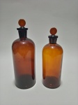 Dois vidros de farmácia âmbar com tampa, sendo um com +/- 550 ml e outro com + - 400 ml. Med. Alt. 20 cm. Diâm. 8 cm. / Alt. 17 cm. Diâm. 7 cm.