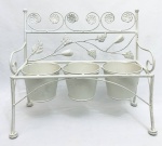 Suporte para três vasinhos de planta, em formato de banco, em metal, decorado com folhas em relevo. Med. 36x18x34 cm. Diâm. do suporte de vaso: 11 cm.