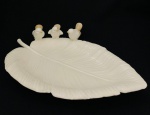Delicada bandeja em formato de folha, ornada com três passarinhos, em porcelana. Med. 30x22 cm.