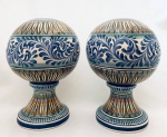 Par de pinhas redondas em faiança, pintadas à mão nas cores branco, azul e mostarda. Med. 27x20 cm.