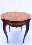 Mesa em madeira nobre com rica marchetaria de ramos e arabescos no tampo e na saia, quatro pés abaulados com bronze na parte final. Med. 75x76 cm.