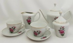 Jogo de chá com um bule, uma leiteira um açucareiro, duas xícaras de chá e dois pires, em porcelana Pozzani, branca com decoração floral.