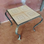 Antiga mesinha em ferro com pés retorcidos e tampo de azulejos cambiáveis . Mede: 33x33x33 cm 