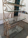 Grande estante / adega em ferro dourado com dobramento ricamente ornamentada e prateleiras em vidro bisotado. Mede: 123x50x20 cm 