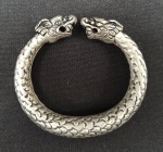 BIJUTERIAS, uma (01) pulseira/bracelete de metal prateado, rígida,com cabeça dupla de dragão, corpo imitando escamas, medidas internas 6x5cm.