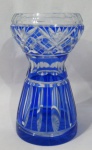 CRISTAIS - Um vaso floreira em cristal double azul, moldado no estilo "cintura fina", decorado com rica lapidação de caneluras, motivos geométricos, sulcos, dedão e palmas, borda facetada, fundo estrelado. Medidas alt 19,5 cm x diam 8,5 cm. Vaso com rachado na base.