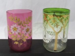 VIDRO - Dois copos confeccionados em vidro decorados com pintura feita à mão; sendo A: em vidro double verde, com decoração de guirlandas de flores e folhas, pontilhados, cruzetas e arabescos nas tonalidades branco e dourado, medindo alt 10 cm x diam 6,3 cm; B: em vidro rosa, ornamentado com folhas flores esmaltadas nos tons dourado, rosa bebê e amarelo, medindo alt 9,5 cm x diam 6,2 cm.