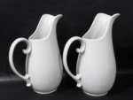 PORCELANA - Par de jarras produzidas em porcelana esmaltada e vitrificada branca, moldadas em feitios diferenciados, alças vazadas. Medidas alt 26,5 cm x larg total 19,5 cm.
