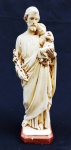 ARTE SACRA, uma (1) imaginária representando São José com Menino Jesus no colo, confeccionada em estuque na tonalidade creme, medindo 22 cm altura, possui pequenos defeitos.