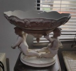 Antigo centro de mesa Italiano, bandeja removível, de porcelana branca, sustentada por 2 anjos segurando uma flor, parte inferior com uma pinha invertida. Med. 30cm x 25cm x 24cm