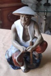 Esplendorosa Estatueta de figura oriental sentada na pedra elaborada com cerâmica vitrificada com vestimenta branca e ocre. Alt.18cm
