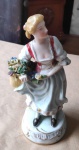 VIEIRA DE CASTRO - Porcelana - Figura de dama com cesto de florais, com vestidos representando dama europeia de época, sobre base de porcelana branca com 20cm de altura, peça numerada.