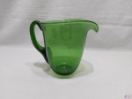 Jarra para água sucos em grosso vidro verde. Medindo 21,5cm bico alça x 18,5cm de altura. Com leve fio de cabelo na base da alça.