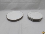Jogo de 7 pratos em porcelana com friso prata. Sendo 2 pratos rasos e 5 pratos de sobremesa. Medindo os pratos rasos 25cm de diâmetro.