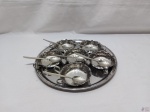 Bandeja redonda com 6 taças de sobremesa com colher em aço inox, sendo as taças em aço inox Meridional. Medindo as taças 10cm de diâmetro x 3,5cm de altura.
