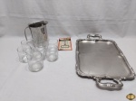 Lote diverso, composto de bandeja em aço inox, jarra em aço inox, 7 copos em vidro e saca rolha em metal. Medindo a bandeja 40cm x 30cm.