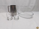 Lote composto de travessa oval em vidro temperado, 2 copos de whisky em vidro com base pesada e jarra em aço inox. Medindo a travessa 30cm x 21cm x 6cm de altura