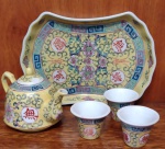 Miniatura de jogo para chá em porcelana oriental, composto por cinco(5) peças, decorado com motivos típicos da procedência nas cores azul e amarela. Apresenta discreto bicado na tampa. Medindo a bandeja 17 x 11 cm.