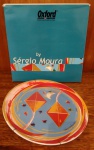 SERGIO MOURA - OXFORD -Prato decorativo com decoração policromada representando pipas. Novo!! Na caixa!! Medindo 25 cm de diâmetro.
