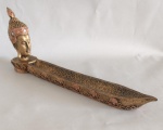 Porta incenso com escultura de cabeça de Indu com patina na cor bronzeada e embelezada com pedrinhas. Medindo 31 cm de comprimento x 4 cm de largura.