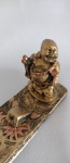 Porta incenso com escultura de Buda Sorridente com patina na cor bronzeada Medindo 28cm de comprimento x 4 cm de largura.