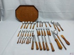 Parte de faqueiro com 42 peças em aço com pega em ratam trançado e bandeja facetada em madeira. Parte de faqueiro composto de 6 garfos de mesas, 6 facas de mesa, 7 colheres de sopa, 1 colher de sobremesa, 7 colheres de chá, 7 colheres de café e 8 peças de servir. Medindo a bandeja 37,5cm x 27,5cm. A colher de arroz está com leve perda na pega.