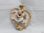 Enfete na forma de anjos em porcelana, possivelmente Espanhol. Medindo 22cm x 16cm. Peça com restauro e perda na asa e bicados nas laterais.