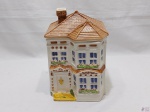 Caixa biscoiteira em porcelana na forma de casa. Medindo 15,5cm x 15,5cm x 23,5cm de altura.