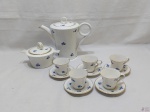 Jogo de servir café em porcelana portuguesa Vista Alegre flor azul com friso ouro. Composto de 5 xícaras com pires, bule e açucareiro. Medindo o bule 19,5cm de altura com tampa.