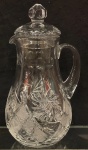 Fina jarra em cristal europeu com tampa,                                                                                   decorada com lapidações geométrica e flores no bojo.                                                                Altura 27 cm