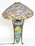 Belíssima luminária de mesa padrão Tiffany (mesma fundição) estilo Art Noveau elegantemente executado com 3 (três) luzes, cúpula em pasta de vidro floral multicolorido, base em bronze com rico trabalho, Impecável estado de conservação. Comprado nos EUA há 20 anos. Em perfeito estado. Obs: a fundição é idêntica a da Tiffany, conhecida como Favrile, e projetado com pedaços de um tipo especial de vidro fundido com óxidos metálicos, no abajur Tiffany este vidro ganha diversas tonalidades, formando um pequeno vitral no abajur. No processo de fabricação do abajur são utilizadas técnicas nas quais são usam-se fitas de cobre soldadas que, junto ao pequeno vitral, formam uma peça de aspecto único. Possui uma base com pátina em tons de marrom. Medida: Alt 0.64 diâmetro 0.50; Nota: Uma peça similar a esta foi vendida para a atriz Barbra Streisand por U$1.000000,00