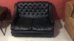 Sofá preto para dois lugares forrado com couro ecológico revestido em capitonê. Medidas: 125 comp x 86 cm prof x 82 cm alt