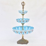 Fruteira em cristal em três estágios  com pratos em overlay azul e pequenas flores pintadas  em  rica policromia, guarnição de metal dourado. Áustria, século XX. Medida: Alt. 53 cm - diam. 28 cm.