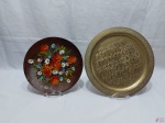 Lote de 2 pratos decorativos, sendo um em madeira com pintura floral e um em latão cinzelado. Medindo o prato de latão 30cm de diâmetro.