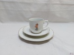 Trio infantil composto de caneca, prato raso e prato de sobremesa em porcelana Real. Medindo o prato raso 18,5cm de diâmetro.