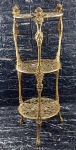 Mesa cantoneira de 3 (três) estágios em bronze amarelo sobre base tripóide decorada por querubins, volutas e acantos. Mede 73 cm de altura por 25 cm de diâmetro. Em excelente estado!