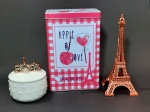 Lote contendo 3 itens decorativos representando Paris: 1 torre Eiffel em tom rosé, 1 lata porta objetos retangular e 1 porta jóias em porcelana decorado pela palavra `Paris` em sua pega. Maior tamanho 19 cm.