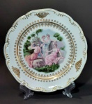 PORCELANA SCHMIDT - Prato decorativo em porcelana de manufatura Schmidt representando cena de pajens em policromia e aplicação de ouro nas bordas. Mede 24 cm de diâmetro.