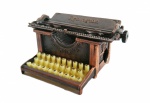 Peça de coleção: Apontador em bronze com imagem de máquina de escrever antiga.