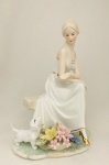 Escultura de dama com cão e flores, em porcelana. Med. 27x20 cm.