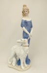 Escultura de dama com cão, em porcelana. Med. Alt. 30 cm.